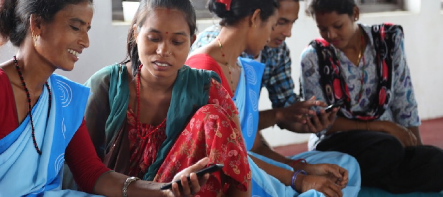 Female Community Health Volunteers seated together using mobile phones
